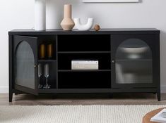 a living room with a black entertainment center and vases on the sideboard next to it