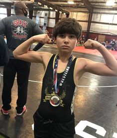 a young man standing on top of a wrestling mat