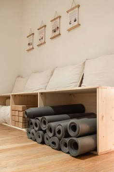 several rolled up yoga mats are on the floor in front of a bed with pillows