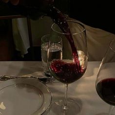 a person pouring wine into two glasses on a table