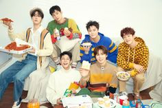 group of young men sitting on a couch eating pizza and drinking soda while posing for the camera