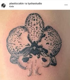 a black and white flower tattoo on the back of a woman's shoulder