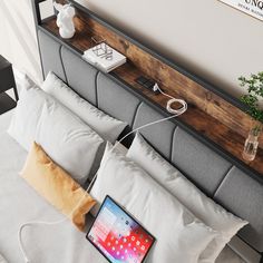 an open laptop computer sitting on top of a bed next to pillows and pillow cases