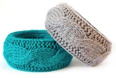 two crocheted bowls sitting next to each other on a white surface, one is blue and the other is gray