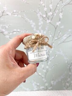 a hand holding a small jar filled with white flowers