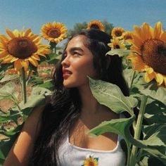 a woman standing in the middle of a field of sunflowers with her eyes closed