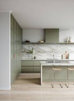 a kitchen with green cabinets and marble counter tops