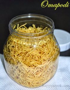 a glass jar filled with yellow shredded noodles on top of a white cloth covered table