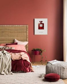 a bedroom with pink walls and bedding in the corner, along with a footstool