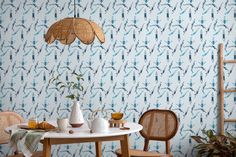 a table with two chairs and a lamp hanging from it's ceiling in front of a patterned wallpaper