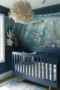 a baby's room decorated in blue and white with an ocean theme on the wall