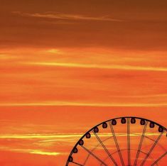 the ferris wheel is silhouetted against an orange sky