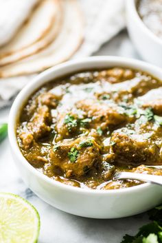 a white bowl filled with meatballs and cilantro next to pita bread