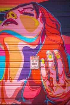 a garage door with a painting of a woman's face and hands painted on it