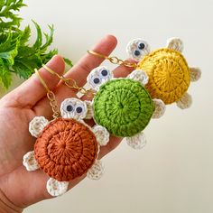 four crocheted keychains with eyes on them in the palm of someone's hand