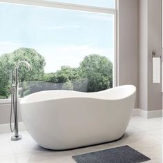 a bathtub sitting in front of a window next to a rug on the floor