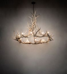 a chandelier made out of antlers with lights hanging from the top and bottom