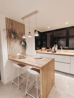 a cat sitting on top of a kitchen counter next to a wooden table and chairs