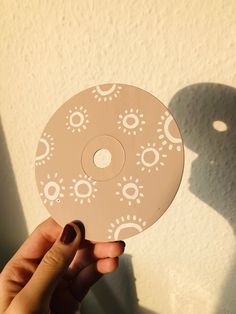 a person holding up a white disc with circles on it in front of a wall