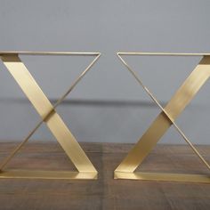 pair of gold metal side tables on wooden floor with grey wall in the back ground