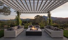 an outdoor living area with couches, fire pit and pergolated roofing