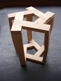 a wooden sculpture sitting on top of a black floor next to a red and white sign