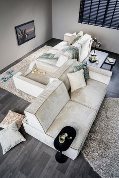 a living room with white couches and pillows on the floor in front of a window