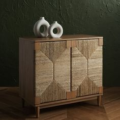 two white vases sitting on top of a wooden cabinet