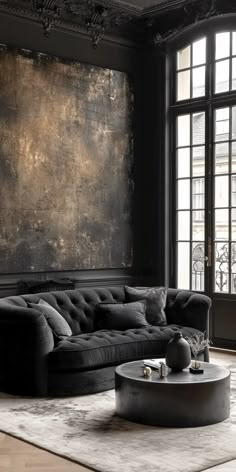 a living room with black furniture and large windows in the background, including a round coffee table