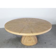 a round wooden table sitting on top of a cement floor