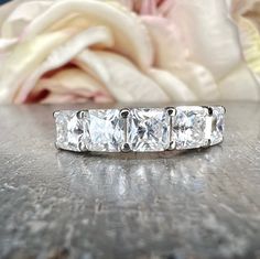 a diamond ring sitting on top of a wooden table next to a rose flower and cloth