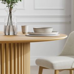 a wooden table topped with a vase filled with flowers next to a white dining chair