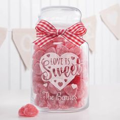 a glass jar filled with candy hearts and the words love is sweet on it's side