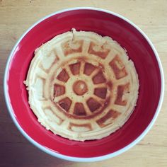 a red and white bowl filled with waffles on top of a wooden table