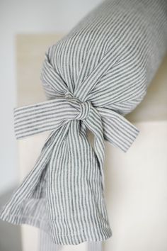 a striped pillow tied up with a bow on it's back and sitting on a white chair