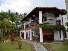 a large white house sitting on top of a lush green field next to palm trees