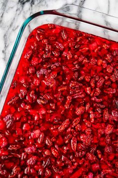 a glass dish filled with cranberry sauce on top of a marble counter