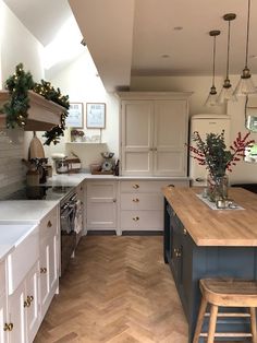 a kitchen with white cabinets and wood flooring is pictured in this image, there are two stools on the counter