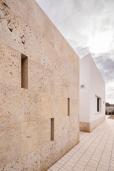 a white building with three windows on the side and a brick walkway next to it