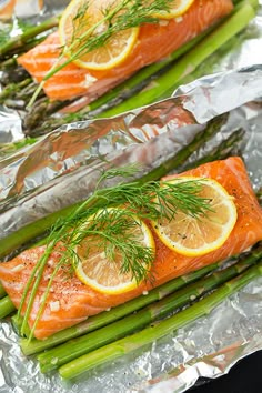 salmon and asparagus wrapped in aluminum foil with lemon slices on the side, ready to be cooked