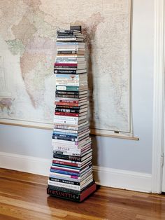 a tall stack of books sitting on top of a wooden floor next to a map