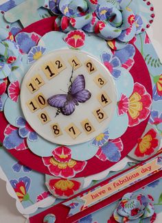 a close up of a clock on a card with flowers and butterflies around it,