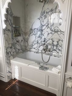 a bathroom with marbled walls and flooring, including a bathtub in the middle