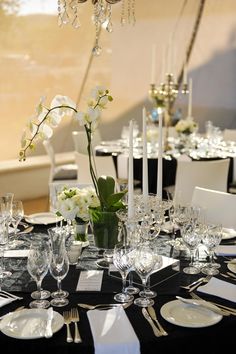 the table is set with black and white linens, silverware, and flowers