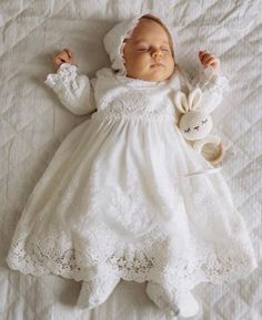 a baby is sleeping on a white blanket with a stuffed animal in it's arms