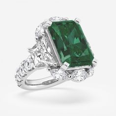 an emerald and diamond ring with three stone accents on the band, set in 18k white gold