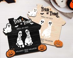 two wooden halloween tags sitting on top of a table next to pumpkins and other decorations