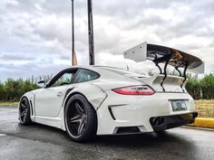 a white sports car parked on the side of the road with a surfboard attached to it's roof