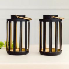 two black and gold candle holders sitting next to each other on a white counter top