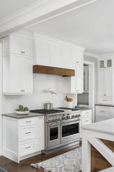 a kitchen with white cabinets and stainless steel stove top oven in the center, along with an area rug on the floor